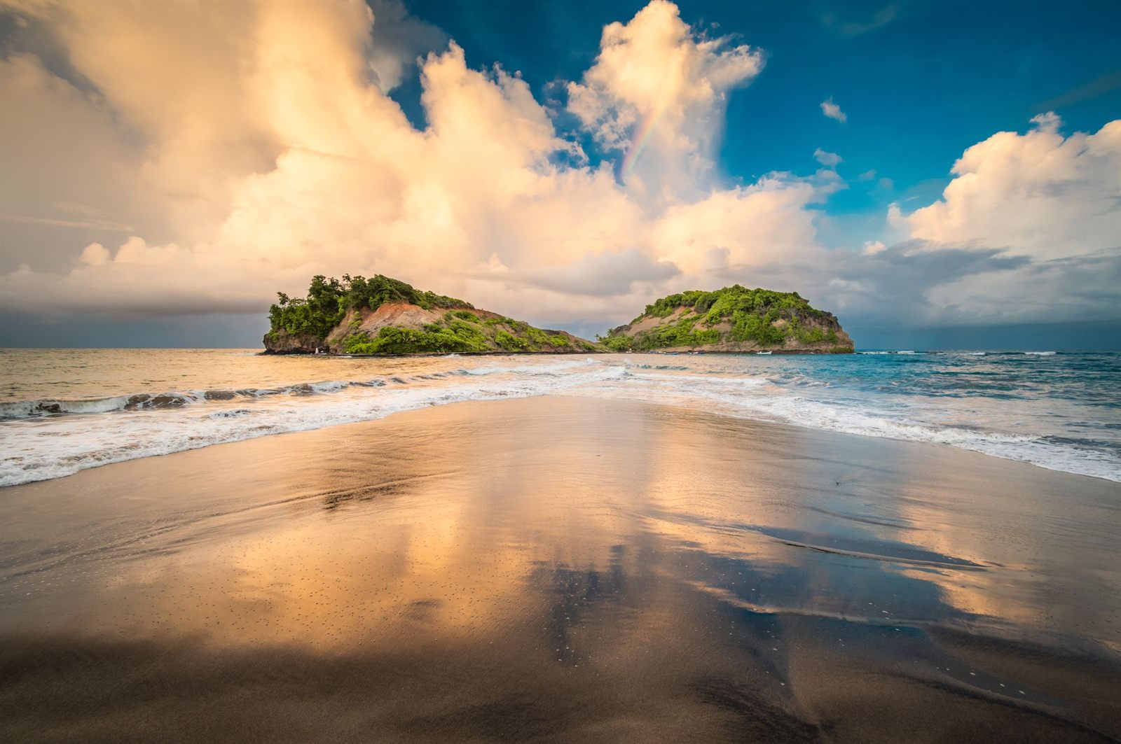 Small green island off a Martinique beach under dramatic clouds