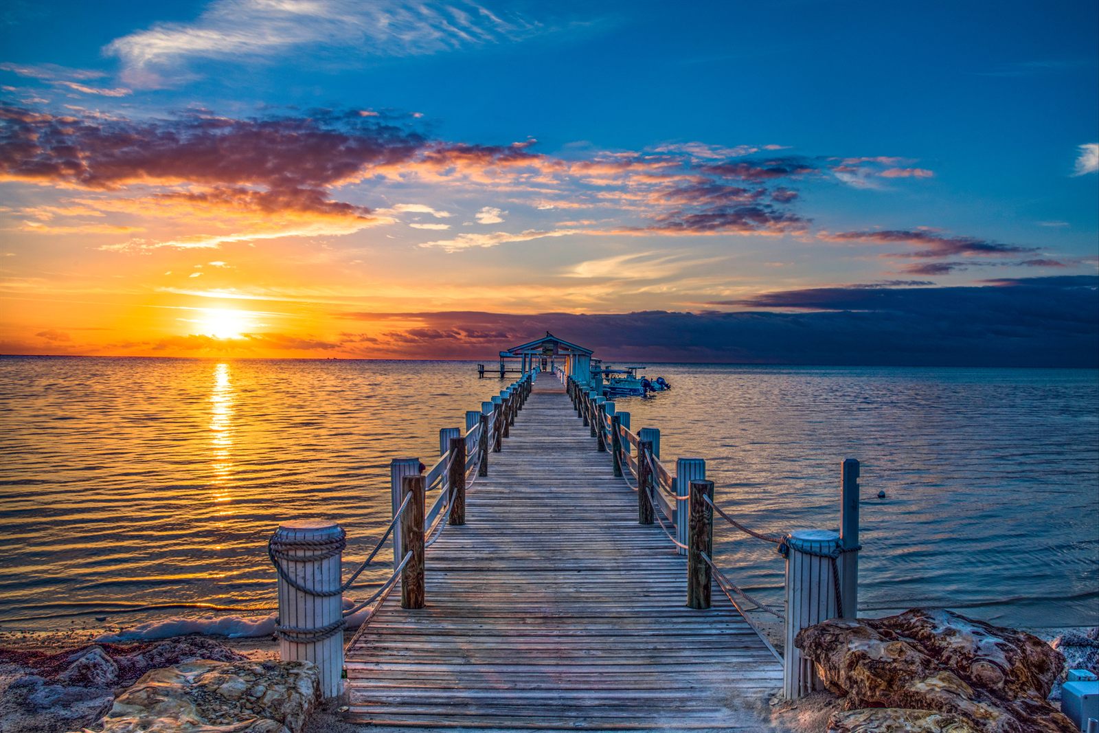 Wooden pier leading out to a sunset over calm water